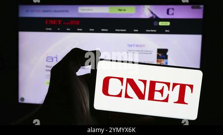 Stuttgart, Deutschland, 06.03.2024: Person, die ein Mobiltelefon mit Logo der amerikanischen Technologie-Medienplattform CNET vor der Business-Webseite hält Stockfoto