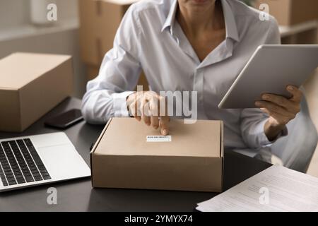 Reife Unternehmerin, die den Barcode auf der Pappschachtel überprüft Stockfoto