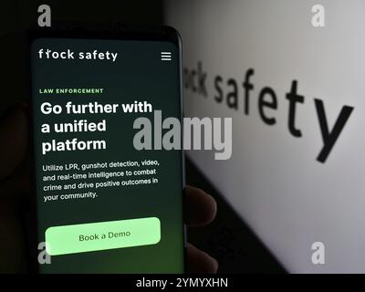 Stuttgart, Deutschland, 06.03.2024: Person, die ein Mobiltelefon hält, mit Webseite des US-amerikanischen Videoüberwachungsunternehmens Flock Safety vor dem Firmenlogo. Fokus Stockfoto