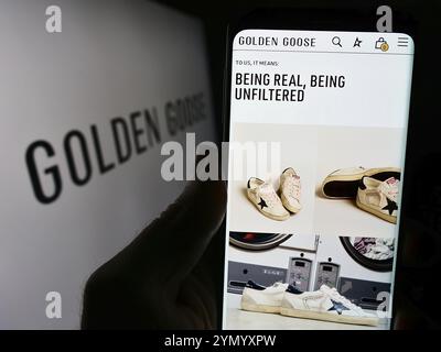 Stuttgart, Deutschland, 03.05.2024: Person, die ein Handy hält, mit Webseite der italienischen Sneaker-Firma Golden Goose S.p.A. vor dem Logo. Konzentrieren Sie sich auf die Mitte Stockfoto
