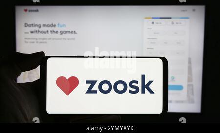 Stuttgart, Deutschland, 03-01-2024: Person mit Handy mit Logo der Online-Dating-Plattform-Firma Zoosk Inc. Vor der Business-Website. Konzentrieren Sie sich auf Stockfoto