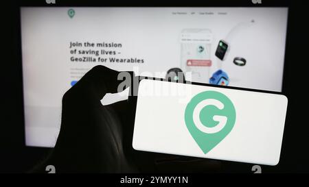 Stuttgart, 24.02.2024: Person, die ein Mobiltelefon mit dem Logo des amerikanischen GPS-Ortungsunternehmens GeoZilla Inc. Vor der Webseite hält. Fo Stockfoto