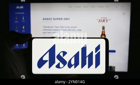 Stuttgart, Deutschland, 18.03.2024: Person, die ein Mobiltelefon mit dem Logo des japanischen Brauunternehmens Asahi Group Holdings Ltd. Vor der Webseite hält. Stockfoto