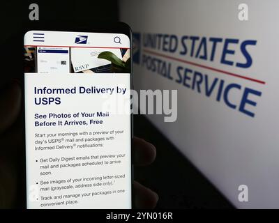 Stuttgart, Deutschland, 14.06.2024: Person, die ein Mobiltelefon hält, mit Webseite der US-amerikanischen Agentur United States Postal Service (USPS) vor dem Logo. Schwerpunkt auf cen Stockfoto