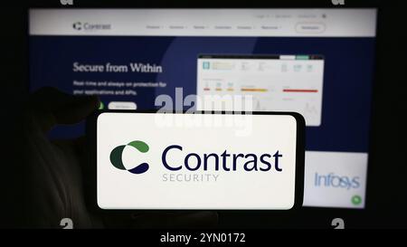 Stuttgart, Deutschland, 14.05.2024: Person, die ein Mobiltelefon mit dem Logo des US-Softwareunternehmens Contrast Security Inc. Vor der Website des Unternehmens hält. Fokus o Stockfoto
