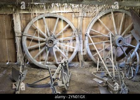 Hölzerne Speichenräder und Pflüge in der Scheune Stockfoto