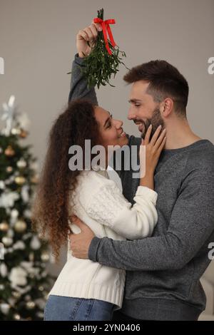 Ein reizendes Paar unter Mistelzweigen im Zimmer, das zu Weihnachten dekoriert war Stockfoto