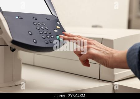 Frau, die drinnen modernen Drucker benutzt, Nahaufnahme. Druckerei Stockfoto