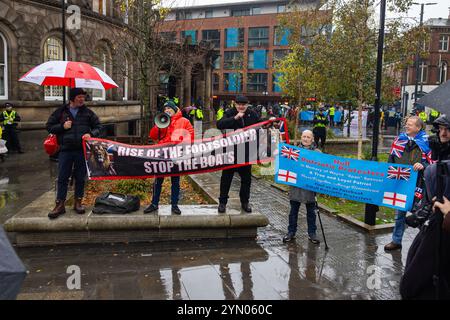 Leeds, Großbritannien. NOVEMBER 2024. Die Demonstranten halten die Schilder „Hull Patriotic Protstors“ und „Rise of the Footsoldier, stop the Boats“ fest, während sich zwei rivalisierende Protestgruppen vor der Leeds Corn Exchange versammelten, unter den widrigen Wetterbedingungen, die durch Sturm Bert verursacht wurden. Quelle: Milo Chandler/Alamy Live News Stockfoto