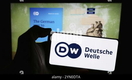 Stuttgart, Deutschland, 04.10.2024: Handybesitzer mit Logo der Deutschen Welle (DW) vor der Webseite. Fokussieren Stockfoto