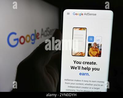 Stuttgart, Deutschland, 17.07.2024: Person, die ein Mobiltelefon hält, mit Webseite des Online-Werbeprogramms Google AdSense vor dem Firmenlogo. Konzentrieren Sie sich auf Stockfoto