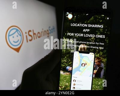 Stuttgart, Deutschland, 24.02.2024: Person, die ein Mobiltelefon mit Webseite des US-amerikanischen Social-Mapping-Unternehmens iSharingSoft Inc. (ISharing) mit Logo hält. Fokus auf ce Stockfoto