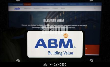 Stuttgart, Deutschland, 13.03.2024: Person mit Mobiltelefon mit Logo der US-amerikanischen Facility Management-Gesellschaft ABM Industries Inc. Vor der Business-Website. Stockfoto