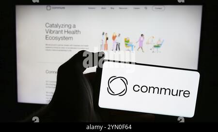 Stuttgart, Deutschland, 21.05.2024: Person mit Mobiltelefon mit Logo des amerikanischen Gesundheitssoftware-Unternehmens Commure Inc. Vor der Business-Webseite. Stockfoto