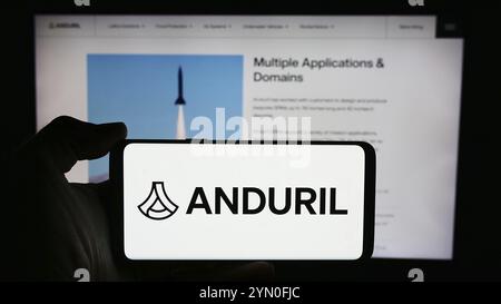 Stuttgart, 21.05.2024: Person, die ein Mobiltelefon mit Logo des US-amerikanischen Verteidigungstechnologieunternehmens Anduril Industries Inc. Vor der Business-Webpa hält Stockfoto