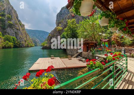 Malerische Bootsfahrt auf dem smaragdgrünen Wasser des Matka Canyon, mit Restaurants und der Kirche St. Andrea in Mazedonien Stockfoto
