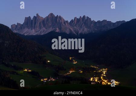 Die Geisler-Gruppe der Dolomiten und des Fünner Val in der Abenddämmerung. Die Kirche Santa Maddalena leuchtet und ist bei Touristen beliebt. Stockfoto