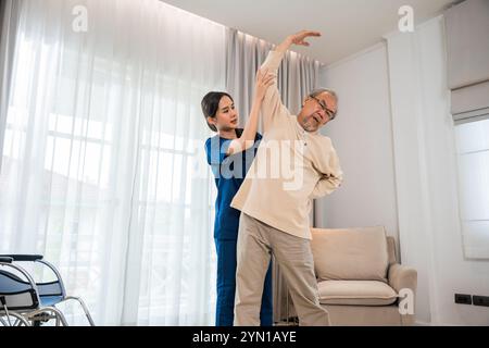 Der alte Senior-Mann trainiert zu Hause gern mit einem Physiotherapeuten für ausgestreckte Arme Stockfoto