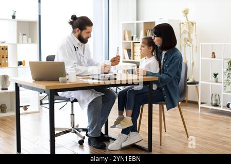 Kaukasischer Arzt, der Mutter und Tochter in der Klinik Medizin anbietet Stockfoto