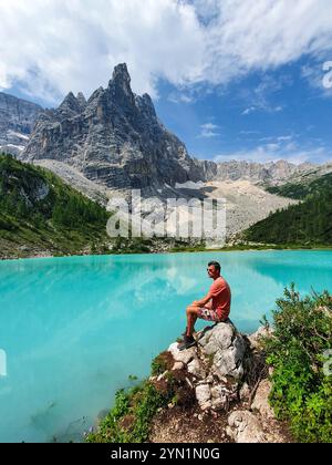 Eine Person genießt eine ruhige Einsamkeit an einem atemberaubenden türkisfarbenen See, umgeben von majestätischen Bergen und üppigem Grün. Lago Di Sorapis Dolomiten Italien Stockfoto