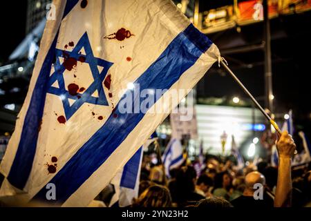 Tel Aviv, Israel. November 2024. Eine israelische Flagge mit roter Farbe wird während einer Demonstration in Tel Aviv am Samstag, 23. November 2024, geschwenkt. Tausende Israelis gingen am Samstagabend auf die Straßen des Landes, um eine weitere Woche in Folge Proteste zu veranstalten, die die Freilassung von 110 Geiseln forderten, die noch immer Gefangenen in Gaza helfen, und um Neuwahlen. Foto von Eyal Warshavsky. Quelle: Eyal Warshavsky/Alamy Live News Stockfoto