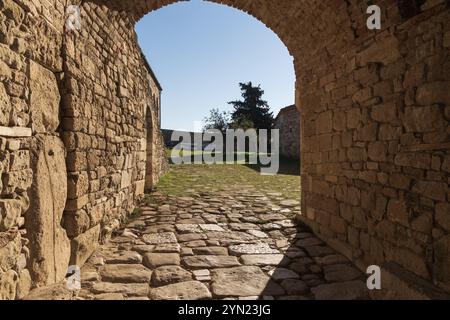 Bogengang mit alten mittelalterlichen Kalksteinmauern mit Kobalt Fußweg Eingang an sonnigen Tagen. Kalksteinmauer, Sandstein Stockfoto