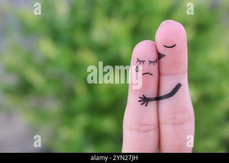 Fingerkunst des unzufriedenen Paares. Die Frau weint, der Mann versichert ihr. Er küsst und umarmt sie. Stockfoto