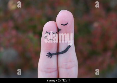 Fingerkunst des unzufriedenen Paares. Die Frau weint, der Mann versichert ihr. Er küsst und umarmt sie. Stockfoto