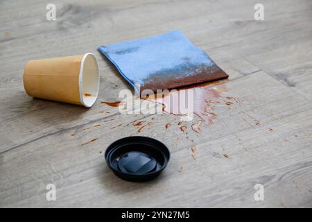 Pappbecher Kaffee fiel auf Laminat, Kaffee verschüttete auf den Boden. Stockfoto