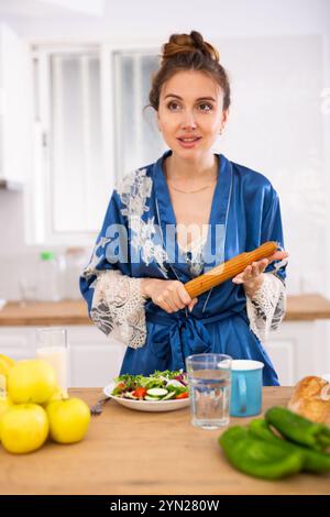 Hausfrau in einem Bademantel mit einer Nadel in den Händen in der Küche Stockfoto