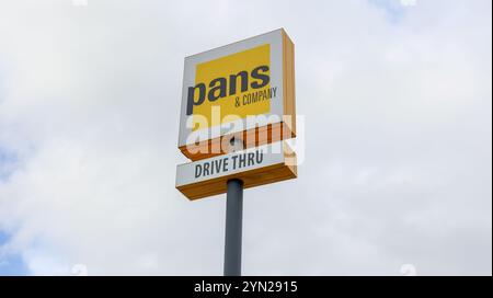 Nahaufnahme einer Pfanne und eines Schildes des Firmenrestaurants, das den Drive-Thru-Service anzeigt, vor dem Hintergrund eines bewölkten Himmels Stockfoto