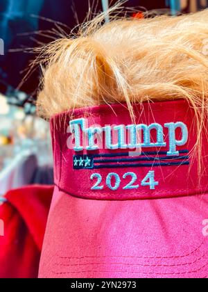 Eine rote Baseballmütze „Make America Great Again“ (MAGA) mit einer gelben Perücke darauf. Stockfoto
