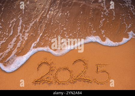 Happy New Year 2025 Konzept, Schriftzug am Strand, Sand und Meereswelle Stockfoto