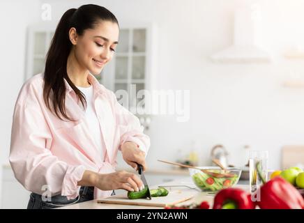 Porträt einer lächelnden jungen Frau, die frischen Salat kocht Stockfoto