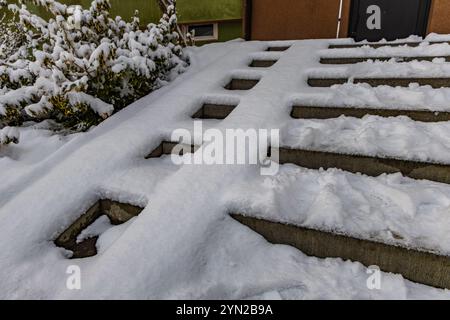 Erster Schneefall, schneebedeckte Treppen und Rollstuhlrampe, die zum Haus führt, Vorsicht vor rutschigen Treppen Stockfoto