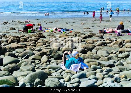 Junge alaskische Frau, die ein Buch liest, während sie sich im Sandy Beach State Park in Sitka, Alaska, USA, entspannt Stockfoto