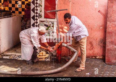 Zwei Männer waschen sich die Hände an einem Hydranten in der Medina von Marrakesch Stockfoto