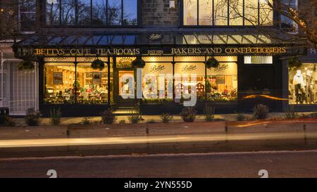 Saisonale Weihnachtsfenster (beleuchtete Straße, Glasdach, Ladenname, Winterabend) - Bettys Café Tea Room, Ilkley, Yorkshire, England Großbritannien. Stockfoto