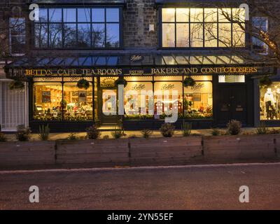 Saisonale Weihnachtsfenster (beleuchtete Straße, Glasdach, Ladenname, Winterabend) - Bettys Café Tea Room, Ilkley, Yorkshire, England Großbritannien. Stockfoto