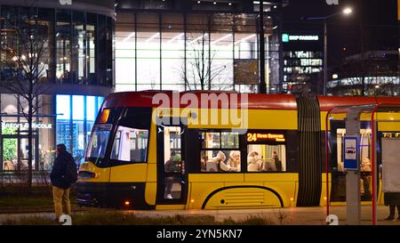 Warschau, Polen. 21. November 2024. Straßenfotografie von Menschen auf der Straße in der Nacht. Die Fußgänger-Silhouetten auf dem Hintergrund des modernen Gebäudes. Stockfoto