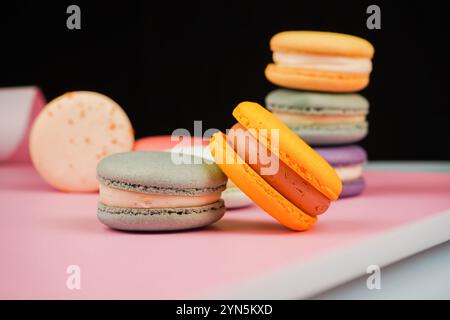 Eine Sammlung bunter Macarons auf einem sanften rosa Hintergrund. Das Foto unterstreicht die zarte und künstlerische Natur dieses klassischen französischen Pas Stockfoto