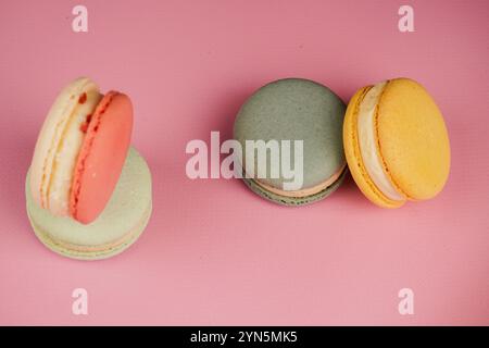 Eine bunte Auswahl an Macarons auf einer Basis mit einem weichen rosa Hintergrund. Dieses delikate französische Gebäck zeigt Eleganz und Geschmack, perfekt für Stockfoto