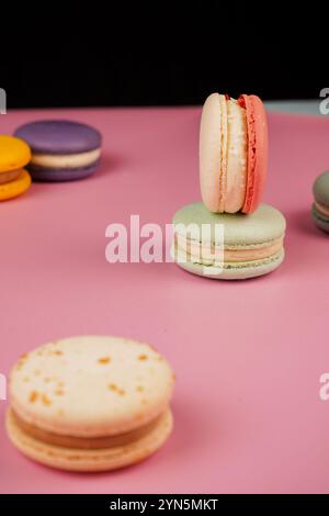 Eine bunte Auswahl an Macarons auf einer Basis mit einem weichen rosa Hintergrund. Dieses delikate französische Gebäck zeigt Eleganz und Geschmack, perfekt für Stockfoto