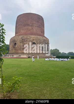 Buddhistische Schüler in weiß gekleidet, wurden auf dem Feld vor dem alten buddhistischen Komplex Sarnath in der Nähe von Varanasi, Indien, unterrichtet Stockfoto