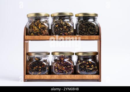 Gläser auf dem Regal mit Teesorten verschiedener Geschmacksrichtungen. Auf weißem Hintergrund Stockfoto
