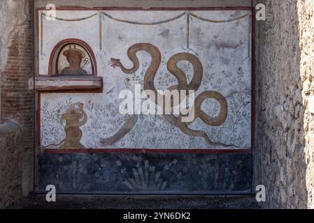 POMPEJI, ITALIEN, 4. MAI 2022, wunderschönes farbenfrohes Fresko einer gelben Schlange, eines Pfaus und einer Frauenbüste in einer Villa Pompejas, Süditalien Stockfoto