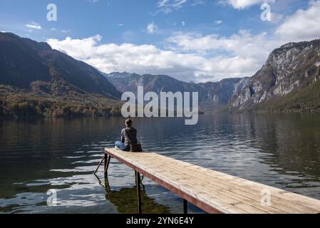 Sitzen Sie auf einem kleinen Steg und genießen Sie den Blick auf die Landschaft des Bohinj-Sees im Triglav-Nationalpark, die Julischen Alpen, Slowenien, Europa Stockfoto