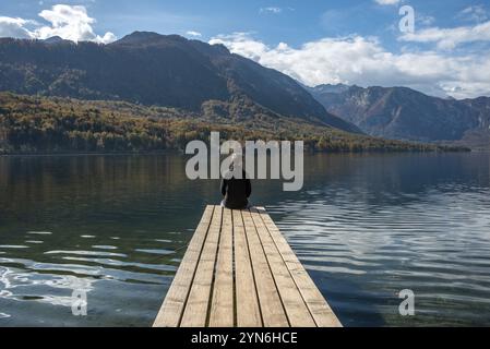 Sitzen Sie auf einem kleinen Steg und genießen Sie den Blick auf die Landschaft des Bohinj-Sees im Triglav-Nationalpark, die Julischen Alpen, Slowenien, Europa Stockfoto