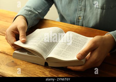 Mann liest die Bibel in englischer Sprache am Holztisch, Nahaufnahme Stockfoto