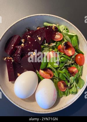 Ein gesundes Frühstück mit einer Schüssel frischen Salat mit Rüben, Kirschtomaten, Nüssen und zwei gekochten Eiern. Die lebendigen Farben sorgen für einen appetitlichen Lo Stockfoto